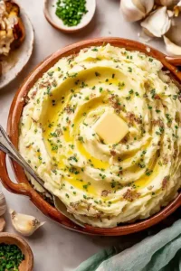 Bowl of creamy garlic mashed potatoes topped with melted butter and chives