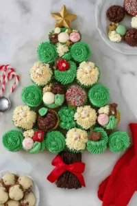 Christmas tree cupcake cake decorated with green and white frosting, candies, and a gold star on top, perfect for Christmas parties.