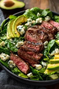 Juicy sliced steak served over spinach with creamy blue cheese and avocado slices