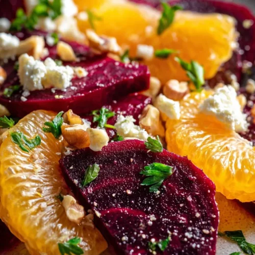 Colorful beet and orange salad garnished with greens in a white bowl
