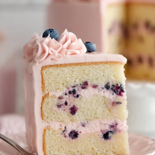 Slice of Blueberry Lemon Curd Cake topped with fresh blueberries and lemon zest