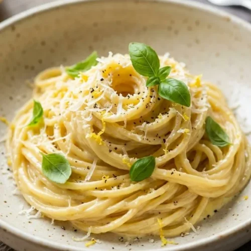 Creamy lemon pasta dish garnished with herbs and lemon zest.