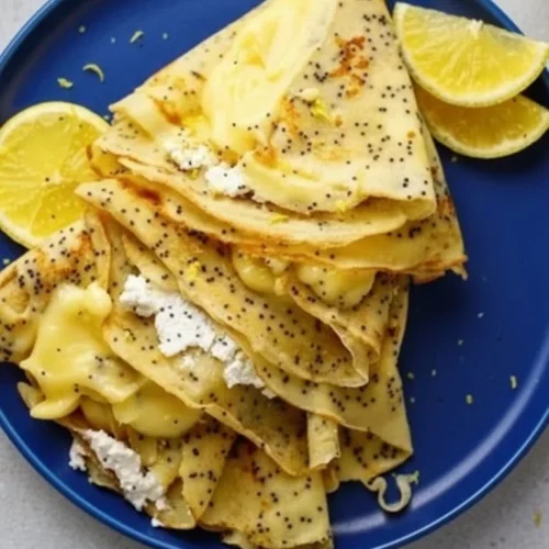 Delicious lemon ricotta crepes served with fresh fruit and a drizzle of syrup.
