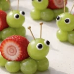Strawberry grape snails in a vibrant garden setting with ripe strawberries and grapes.