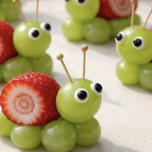 Strawberry grape snails in a vibrant garden setting with ripe strawberries and grapes.