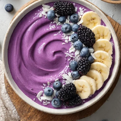 A colorful blueberry banana smoothie bowl topped with fresh fruits and granola