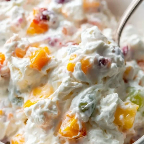 Delicious creamy fruit salad with mixed tropical fruits in a bowl