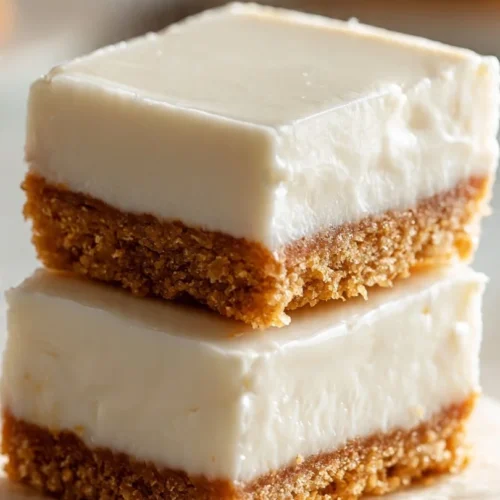 Delicious creamy lemon squares on a white plate with a lemon wedge