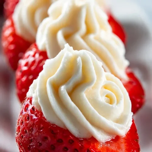 Deviled strawberries filled with cheesecake filling on a white plate.