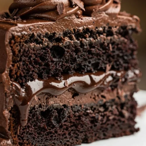 Delicious slice of the best chocolate cake with rich frosting and chocolate shavings