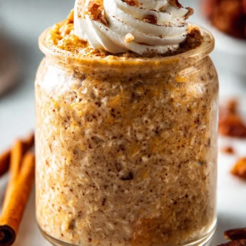 Bowl of pumpkin pie overnight oats topped with whipped cream and spices
