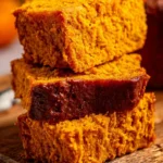 Slice of moist pumpkin bread with spices on a wooden table