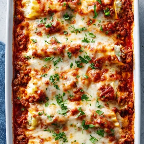 Plate of cheesy lasagna roll ups drizzled with marinara sauce and garnished